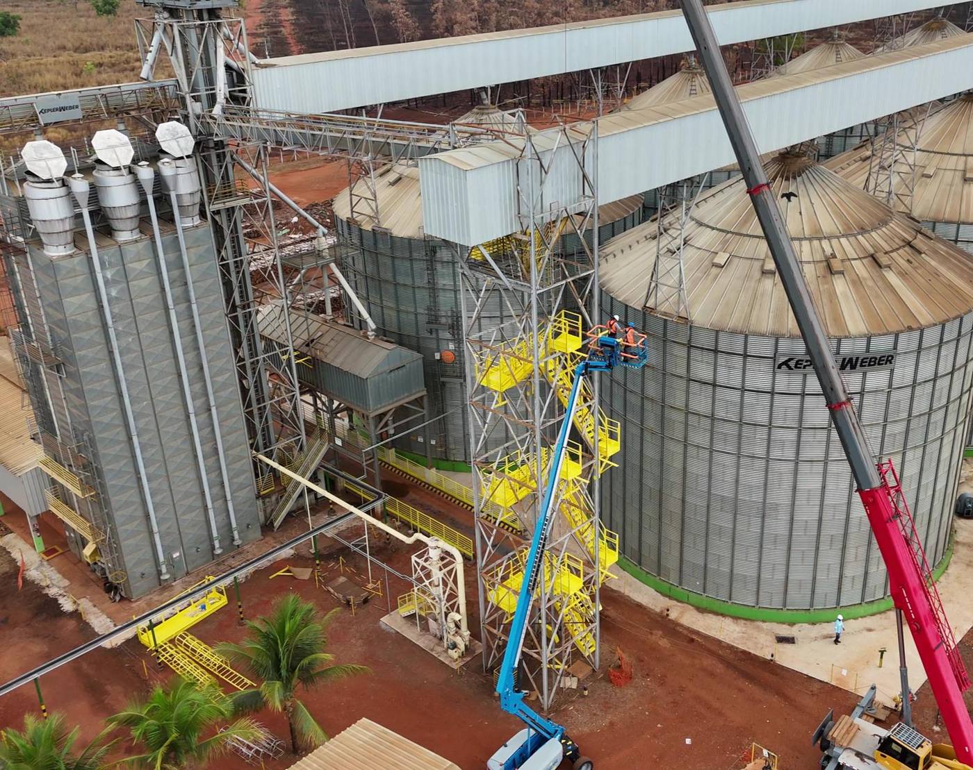Vista aérea de una batería de silos con torre de acceso metálica, escaleras tipo rampa y plataformas en amarillo de seguridad durante el montaje
