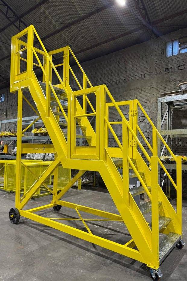 Escalera rampa móvil terminada en amarillo de seguridad dentro de la fábrica